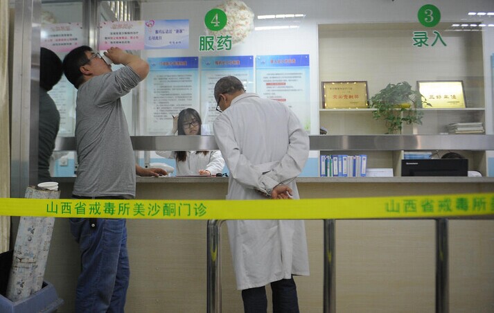在美沙酮门诊大厅,海洛因成瘾者在医护人员的监督下,进行美沙酮服药