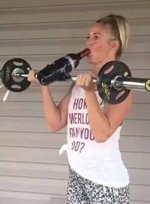 美女边喝酒边健身 举起酒瓶练起肌肉